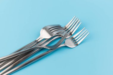 Mavi arka planda çelik çatal. Yemek ve mutfak eşyaları konsepti