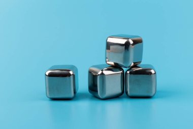 Mavi arka planda izole edilmiş paslanmaz çelik buz küpleri viski taşları. Metin için boşluk.