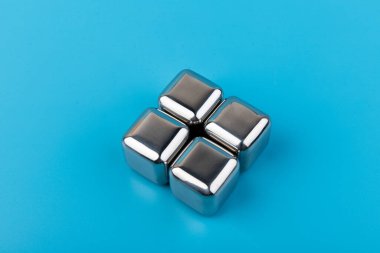 Mavi arka planda izole edilmiş paslanmaz çelik buz küpleri viski taşları. Metin için boşluk.