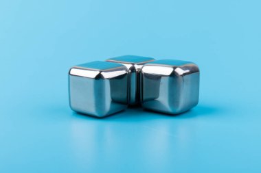 Mavi arka planda izole edilmiş paslanmaz çelik buz küpleri viski taşları. Metin için boşluk.