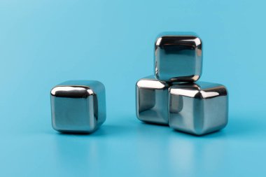 Mavi arka planda izole edilmiş paslanmaz çelik buz küpleri viski taşları. Metin için boşluk.