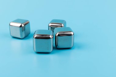 Mavi arka planda izole edilmiş paslanmaz çelik buz küpleri viski taşları. Metin için boşluk.