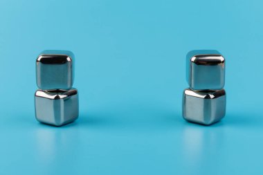 Mavi arka planda izole edilmiş paslanmaz çelik buz küpleri viski taşları. Metin için boşluk.