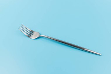 Mavi arka planda çelik çatal. Yemek ve mutfak eşyaları konsepti