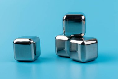 Mavi arka planda izole edilmiş paslanmaz çelik buz küpleri viski taşları. Metin için boşluk.