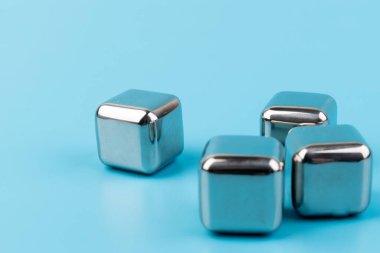 Mavi arka planda izole edilmiş paslanmaz çelik buz küpleri viski taşları. Metin için boşluk.