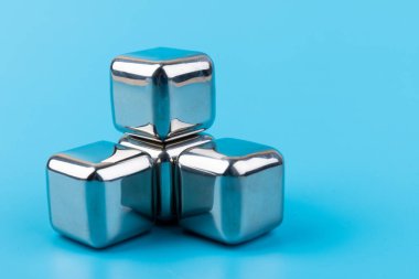 Mavi arka planda izole edilmiş paslanmaz çelik buz küpleri viski taşları. Metin için boşluk.