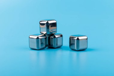 Mavi arka planda izole edilmiş paslanmaz çelik buz küpleri viski taşları. Metin için boşluk.