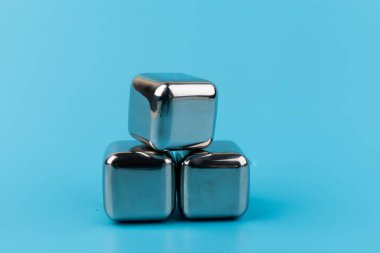 Mavi arka planda izole edilmiş paslanmaz çelik buz küpleri viski taşları. Metin için boşluk.