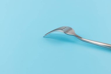 Mavi arka planda çelik çatal. Yemek ve mutfak eşyaları konsepti