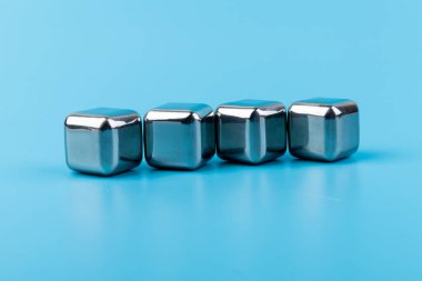 Mavi arka planda izole edilmiş paslanmaz çelik buz küpleri viski taşları. Metin için boşluk.