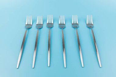 Mavi arka planda çelik çatal. Yemek ve mutfak eşyaları konsepti