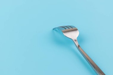 Mavi arka planda çelik çatal. Yemek ve mutfak eşyaları konsepti