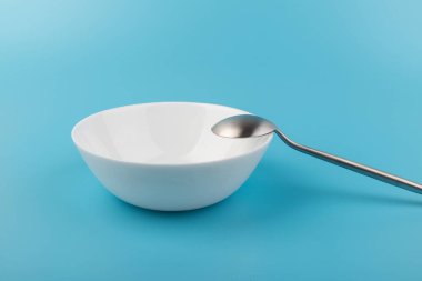 Mavi arka planda kaşığı olan boş bir tabak. Üst Manzara. Mutfak Utensil.