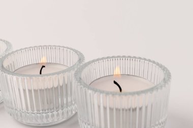 Camdan bir şamdanda yanan mum, beyaza izole edilmiş. Güzel dekor.