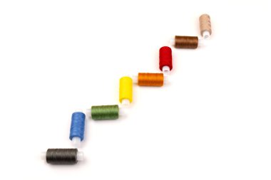 Beyaz arka plandaki makaralara farklı renklerde iplikler dikiyorum. Boş alan, yakın plan.