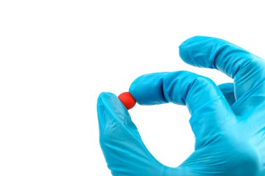Elinde kırmızı haplar olan eldivenli, elinde haplar tutan tıbbi eldivenli bir doktor.