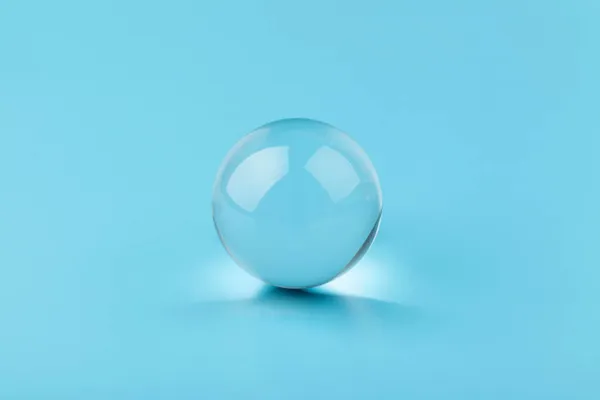 Crystal, transparent ball, sphere on  blue background. Glass.