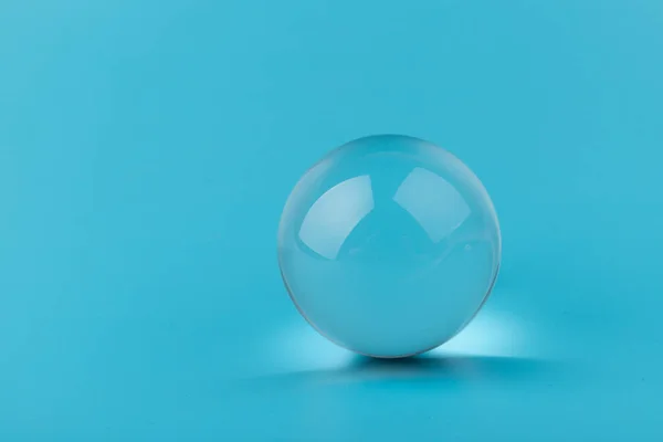 Crystal, transparent ball, sphere on  blue background. Glass.