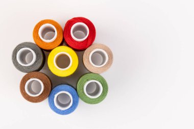 Beyaz arka plandaki makaralara farklı renklerde iplikler dikiyorum. Boş alan, yakın plan.