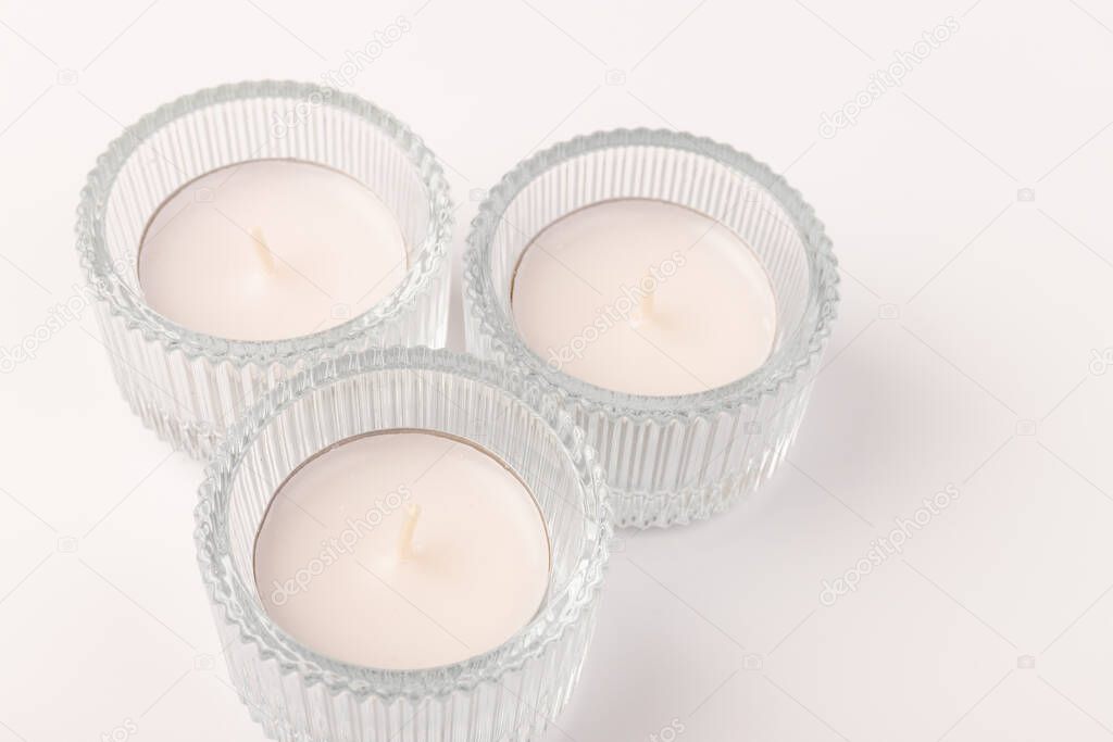 White wax candles in glass holder on white background. Tea light.