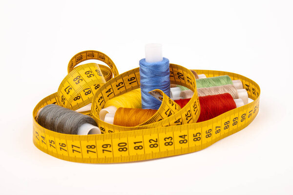 Detail of sewing thread with measure tape isolated on white background. Accessories of tailor or seamstress. 