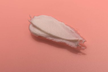 Pembe arka planda beyaz kozmetik krem lekesi. Kremalı temel dokusu. Yüz kremi kokusu. Krem arkaplan dokusu