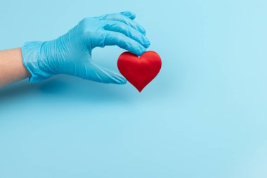 Kadın doktor el ele tutuşup kırmızı oyuncak kalbi kapatıyor. Kardiyoloji kavramı.