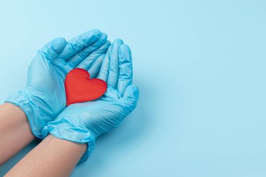 Kadın doktor el ele tutuşup kırmızı oyuncak kalbi kapatıyor. Kardiyoloji kavramı.