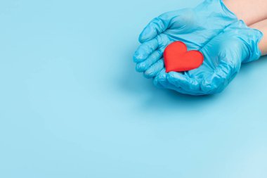Kadın doktor el ele tutuşup kırmızı oyuncak kalbi kapatıyor. Kardiyoloji kavramı.