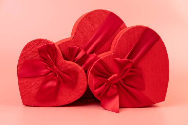 Kırmızı kalp şeklinde hediye paketi ve pembe arka planda kırmızı kurdele. Sevgililer Günün kutlu olsun. Yıldönümü. 