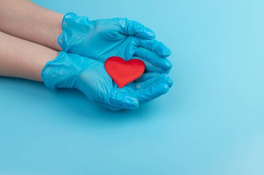 Kadın doktor el ele tutuşup kırmızı oyuncak kalbi kapatıyor. Kardiyoloji kavramı.