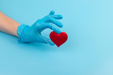 Kadın doktor el ele tutuşup kırmızı oyuncak kalbi kapatıyor. Kardiyoloji kavramı.