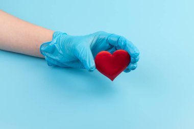 Kadın doktor el ele tutuşup kırmızı oyuncak kalbi kapatıyor. Kardiyoloji kavramı.
