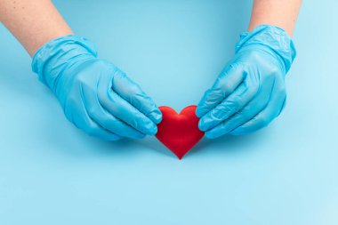 Kadın doktor el ele tutuşup kırmızı oyuncak kalbi kapatıyor. Kardiyoloji kavramı.