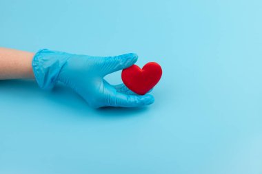 Kadın doktor el ele tutuşup kırmızı oyuncak kalbi kapatıyor. Kardiyoloji kavramı.