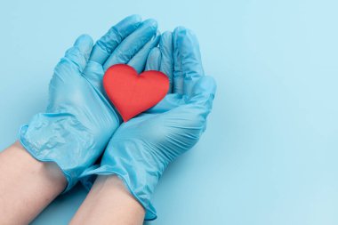 Kadın doktor el ele tutuşup kırmızı oyuncak kalbi kapatıyor. Kardiyoloji kavramı.