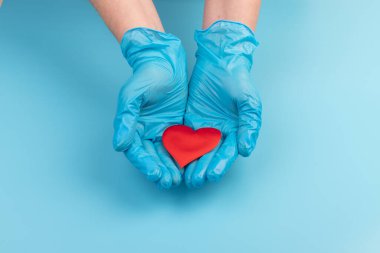 Kadın doktor el ele tutuşup kırmızı oyuncak kalbi kapatıyor. Kardiyoloji kavramı.