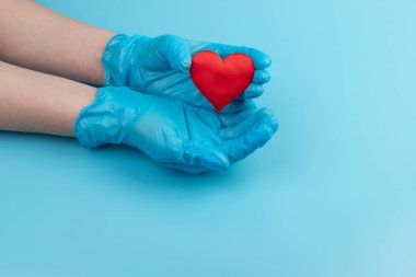 Kadın doktor el ele tutuşup kırmızı oyuncak kalbi kapatıyor. Kardiyoloji kavramı.