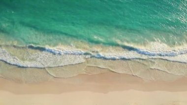 Kum plajı ve mavi denizin havadan görünüşü.