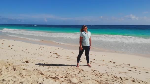 여자는 바닷가에서 몸을 따뜻하게 하고 호흡 운동을 한다 — 비디오