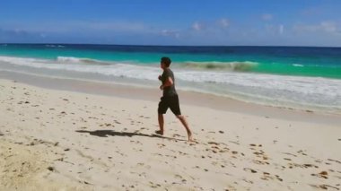 Atletik adam kumsalda okyanus sörfü yapıyor.