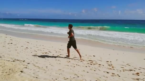 Athletic man run along ocean surf by sandy beach — 图库视频影像