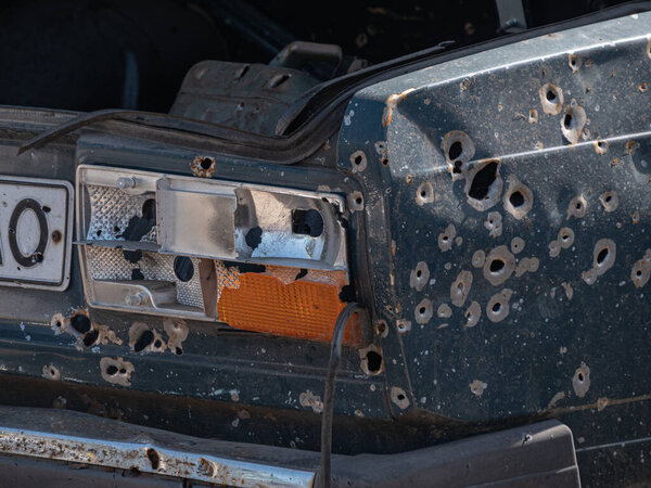 Автомобиль после обстрела из пулемёта и разрезанный осколками из мины, закрыть. Стрельба в автомобилях во время войны на Украине.