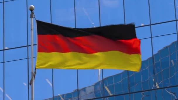 Bandera nacional de Alemania ondea en el viento contra la construcción moderna, de cerca. — Vídeos de Stock