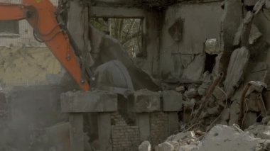 Konut binalarının yıkıntıları üzerinde çalışan kazıcının görüntüsü, yakın çekim