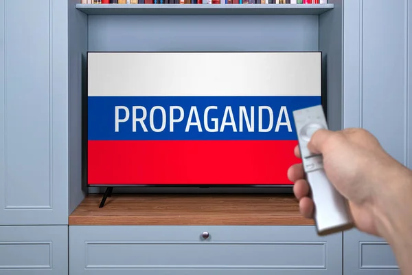 Propaganda kanalları Rus televizyonunda. Modern televizyonda telaş ve Rus propagandası. Yanlış bilgilendirme vatandaşı. Televizyonda Rus haberlerini izleyen adamın uzaktan kumandası. Sahte TV