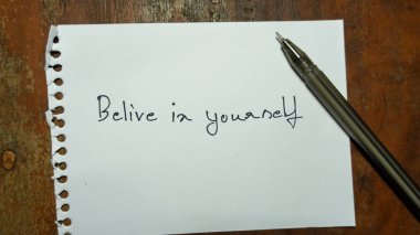 El yazısı motivasyon kelimesi. Kendine inan. Yaşam tarzı motivasyonel pozitif kelimeler tahta bir arka planda yazılı. İş, tabela, sembol, kavram. Kalem ve kağıt. Boşluğu kopyala.