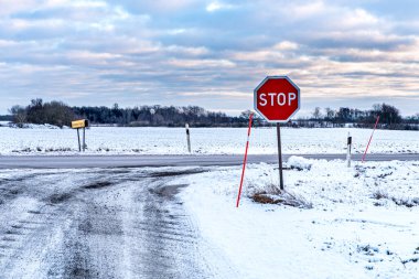 İsveç kırsalında dur işareti olan donmuş bir yol. Soğuk bir İskandinav kışında İskandinav yolu karla kaplıydı. Bulutlar ve buz yalnızlık ve yalnızlık hissini iletir. Hüzün ya da melankolik kavramı - Harsnas doğal rezervi, Skane ilçesi, İsveç