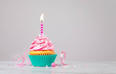 Açık gri arkaplan üzerine mum serpiştirilmiş şirin pembe doğum günü keki. Bir dilek tut.!